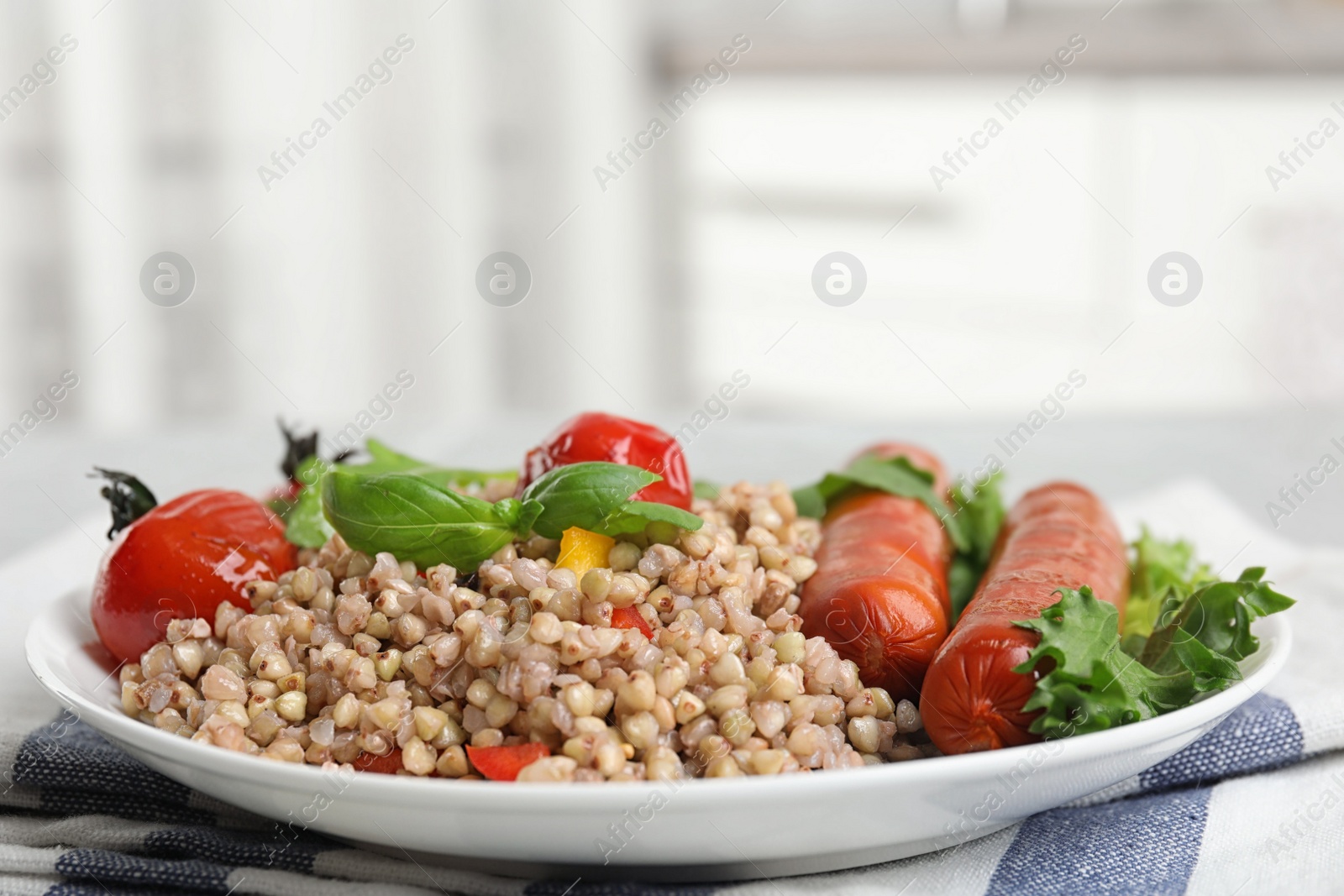 Photo of Plate with tasty buckwheat porridge and sausages indoors, closeup