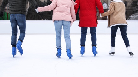 Image of Friends skating along ice rink outdoors, closeup
