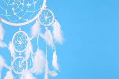Photo of Beautiful handmade dream catcher on light blue background, closeup. Space for text