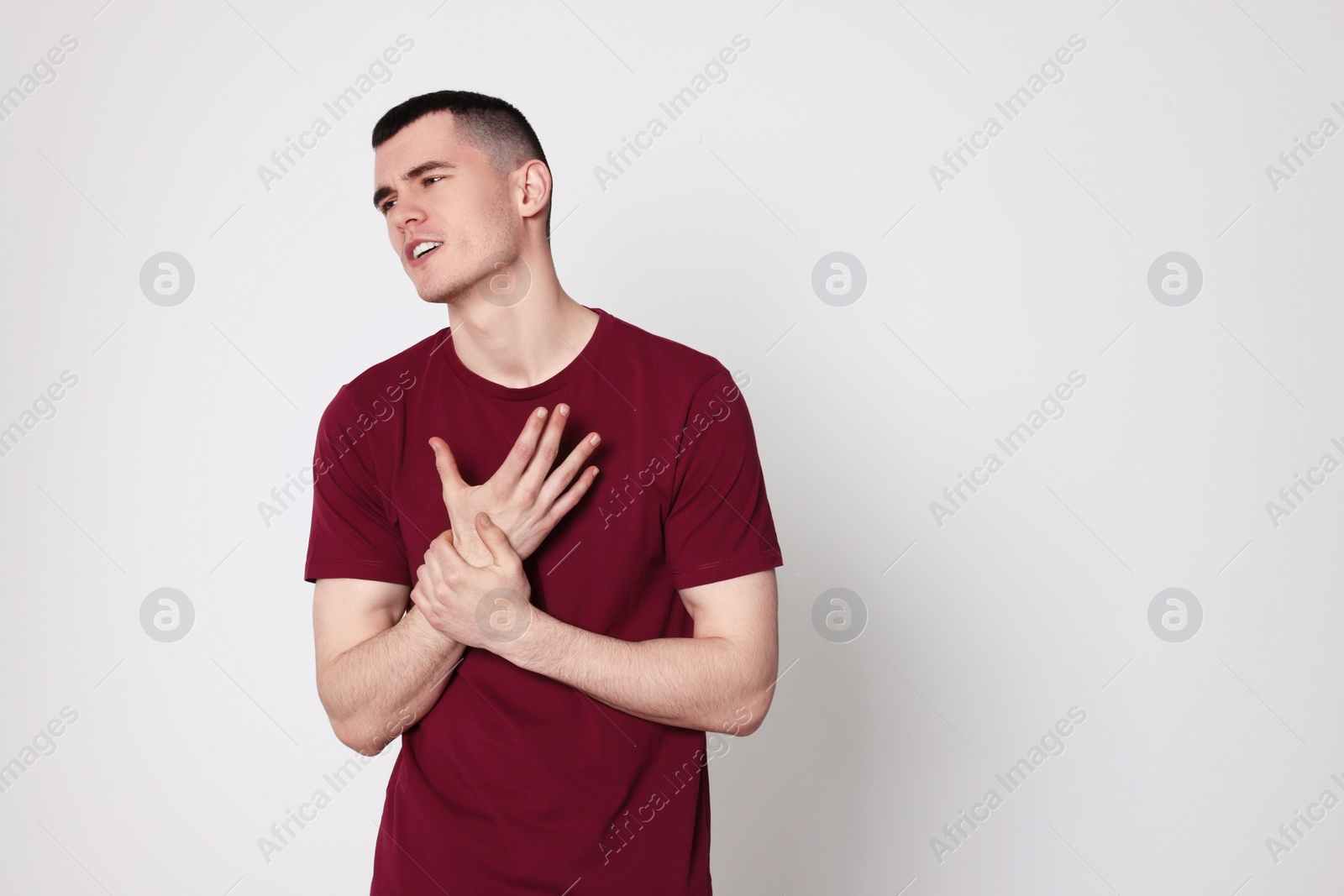 Photo of Man suffering from pain in his hand on light background, space for text. Arthritis symptoms