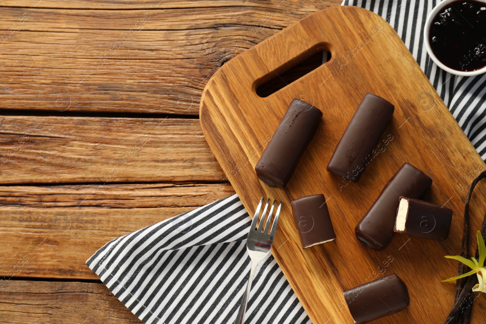 Photo of Glazed vanilla curd cheese bars served on wooden table, flat lay. Space for text