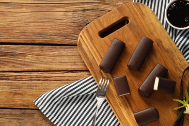 Photo of Glazed vanilla curd cheese bars served on wooden table, flat lay. Space for text