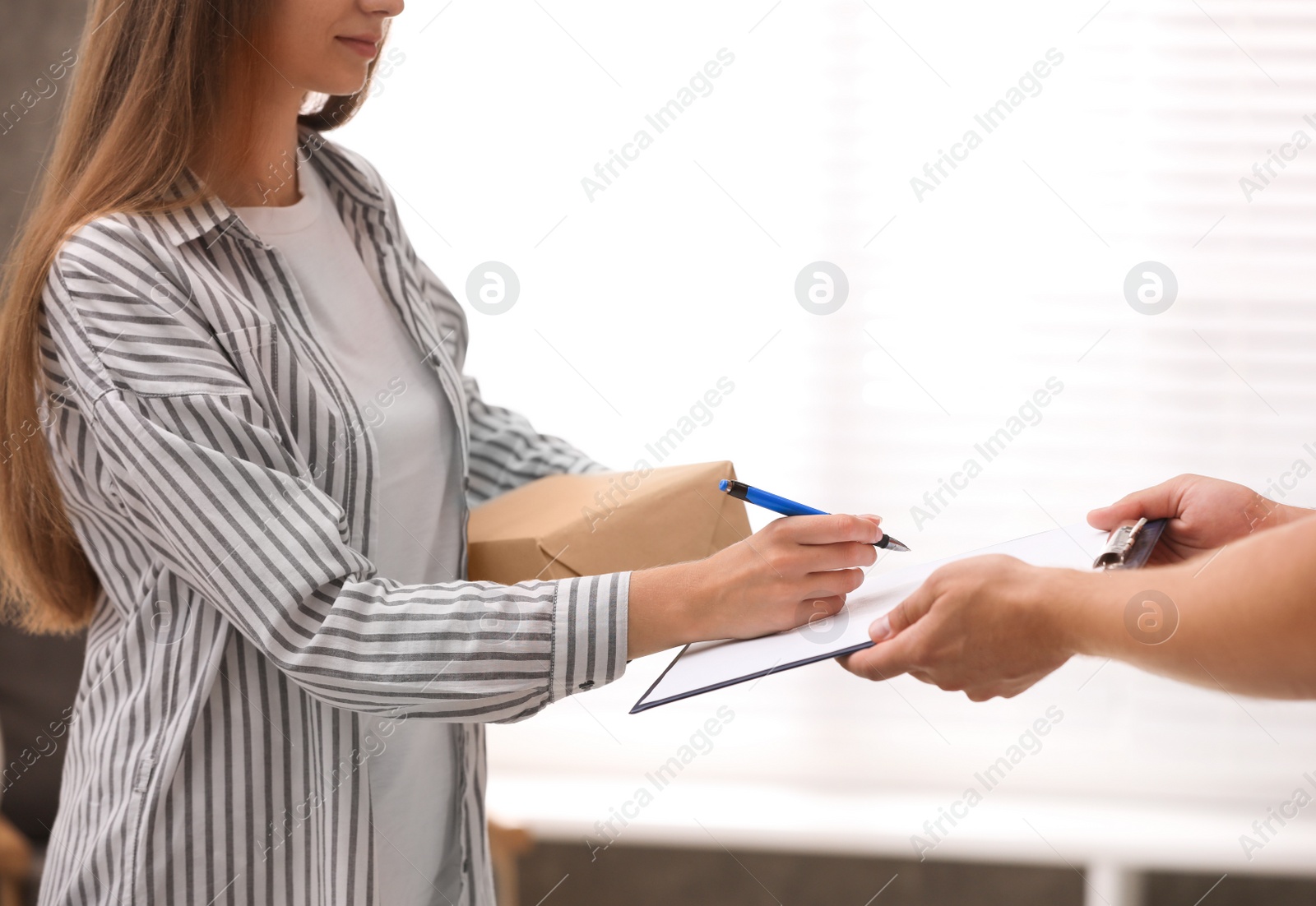 Photo of Woman signing for delivered parcel at home, closeup. Courier service