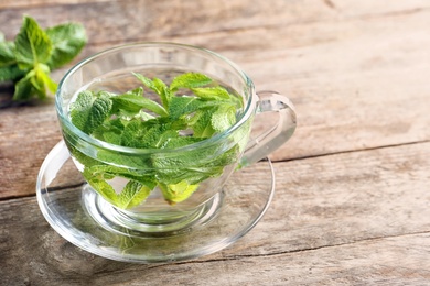 Photo of Cup with hot aromatic mint tea on wooden table