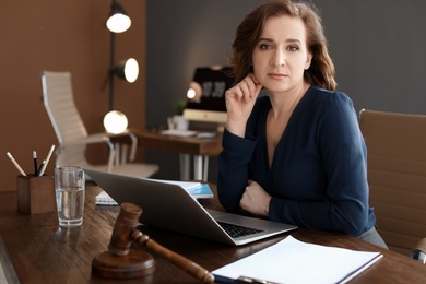 Photo of Female lawyer working with laptop at table in office