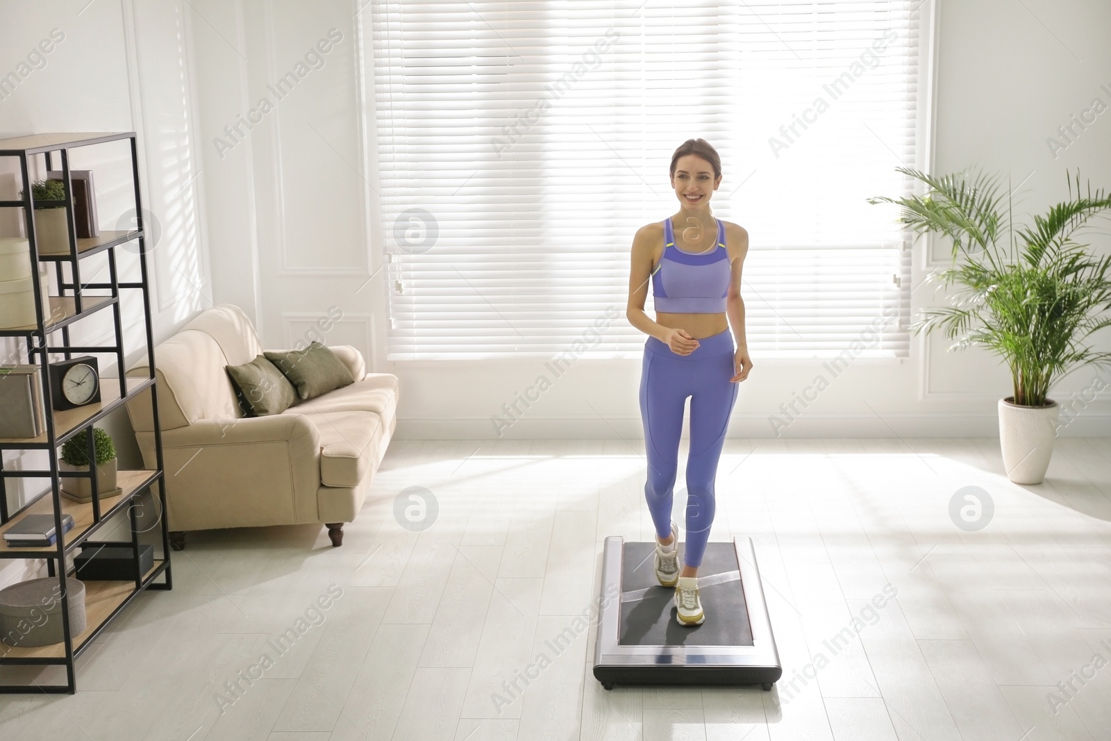 Photo of Sporty woman training on walking treadmill at home