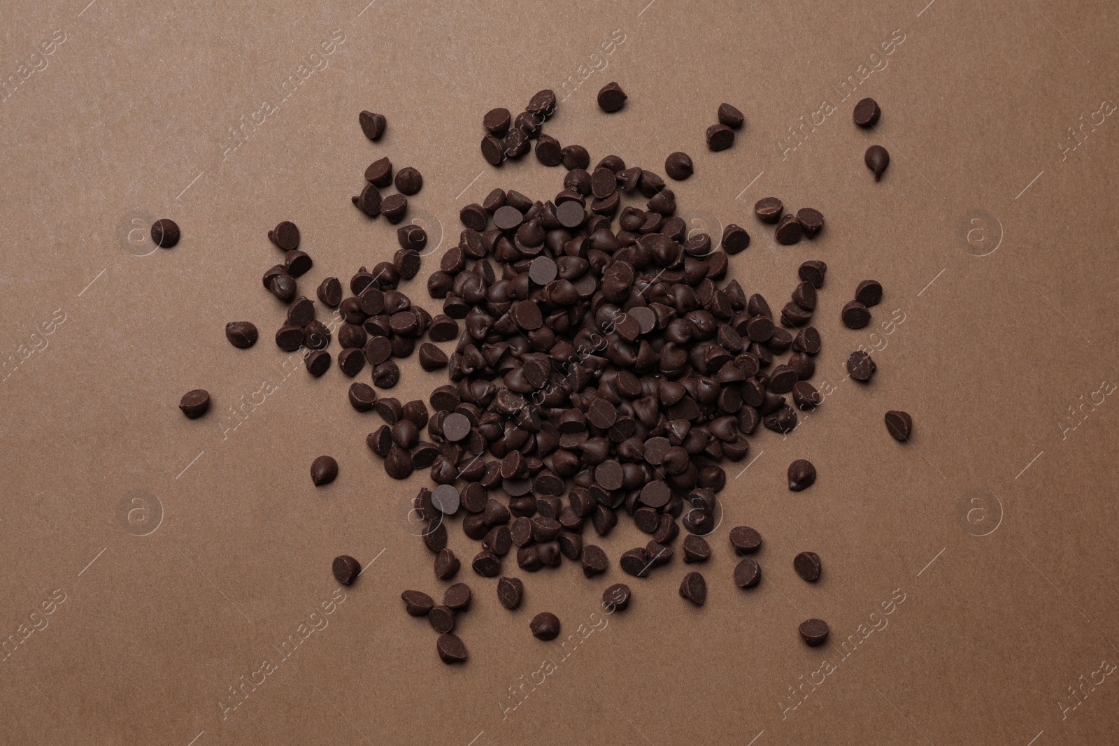 Photo of Pile of delicious chocolate chips on brown background, top view