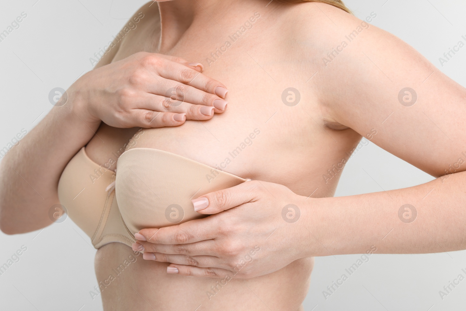 Photo of Mammology. Young woman doing breast self-examination on light grey background, closeup
