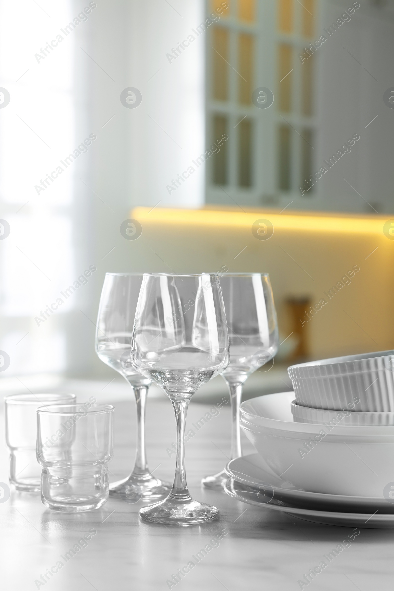 Photo of Different clean dishware and glasses on white marble table in kitchen