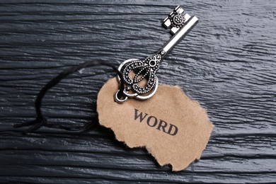 Photo of Key with tag WORD on black wooden background, top view. Keyword concept