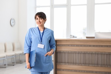Portrait of smiling medical assistant with clipboard at hospital reception