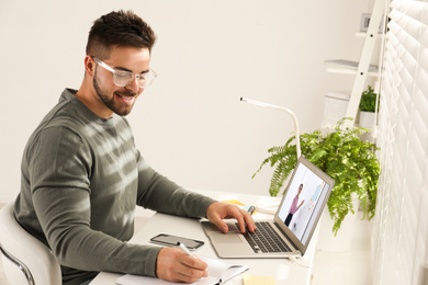Image of Young man watching video at desk indoors. Online learning