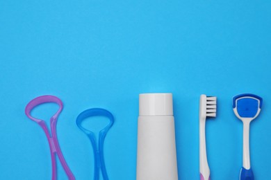 Photo of Tongue cleaners, toothbrush and paste on blue background, flat lay. Space for text