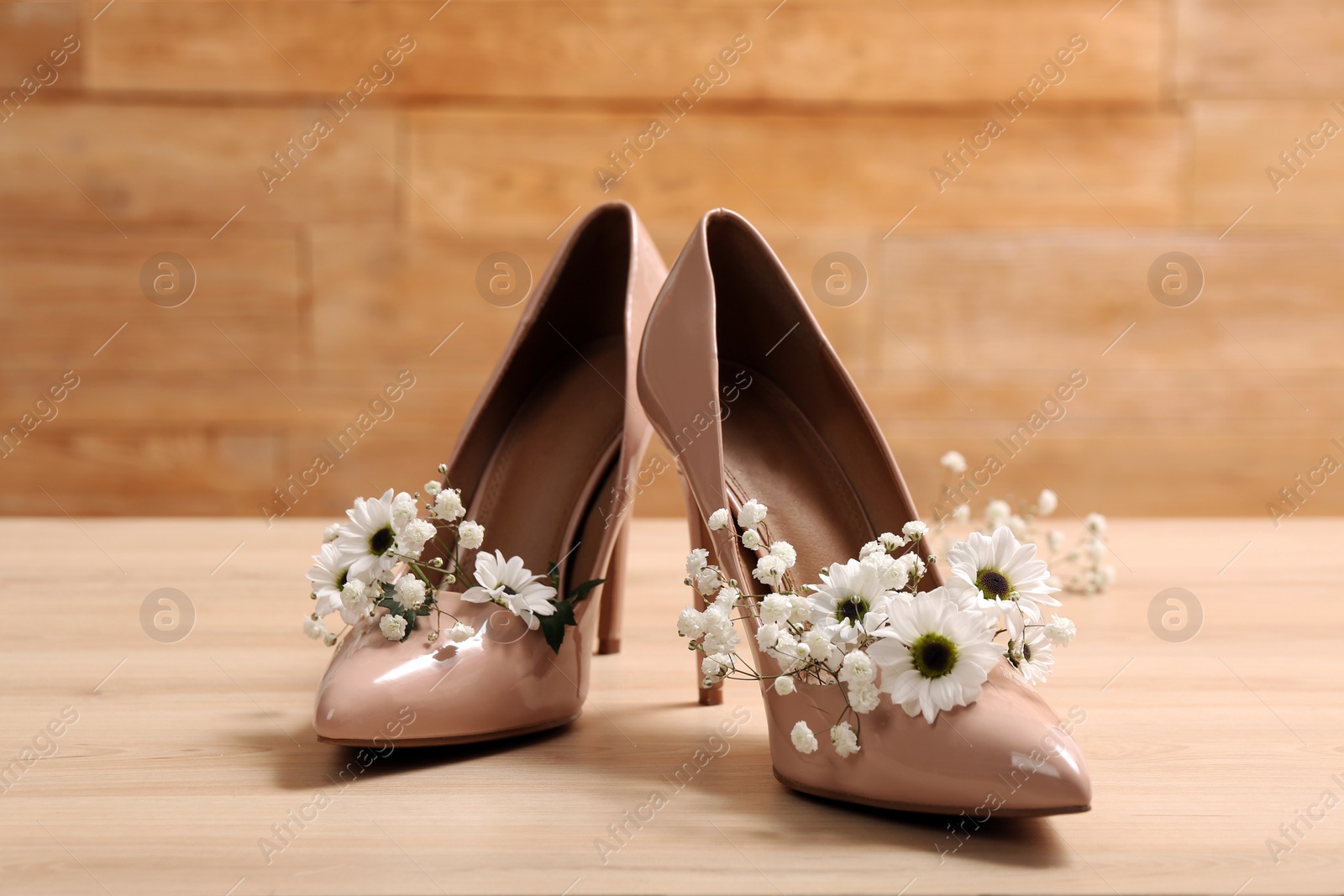 Photo of Women's shoes with beautiful flowers on wooden surface
