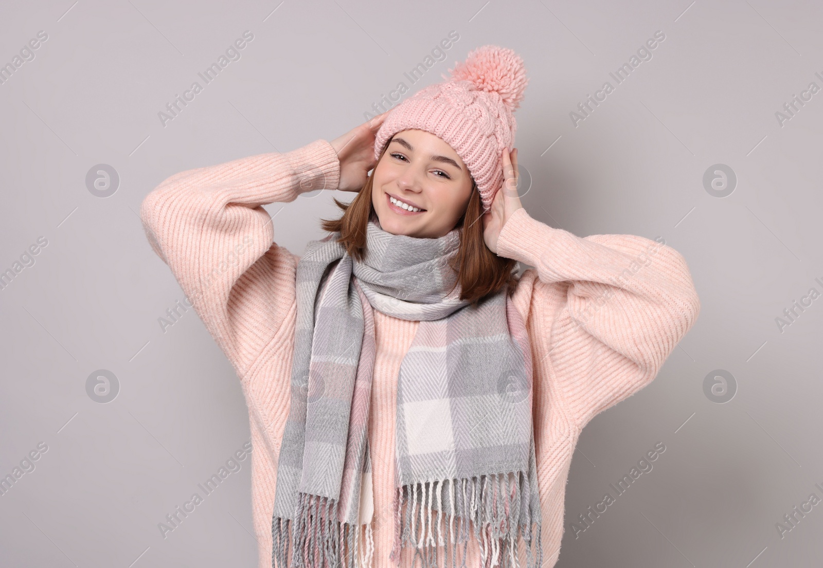 Photo of Beautiful woman in warm scarf and hat on gray background