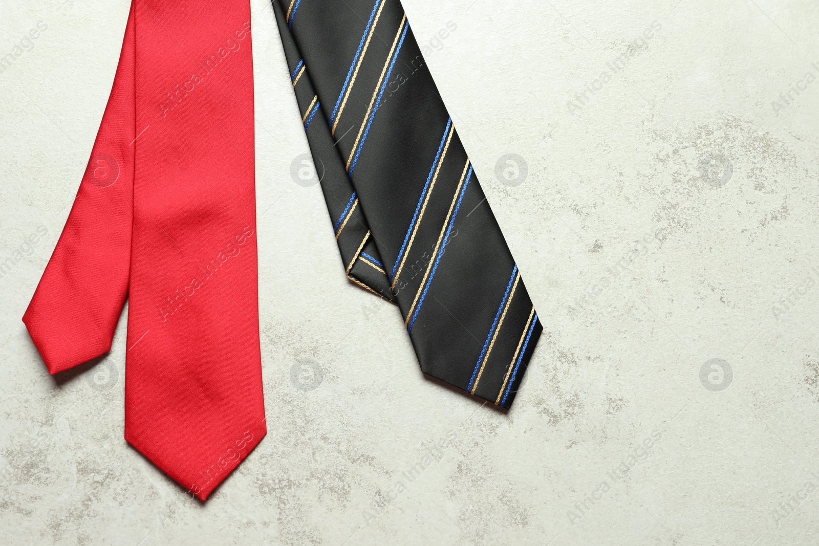 Photo of Two neckties on light textured table, top view. Space for text