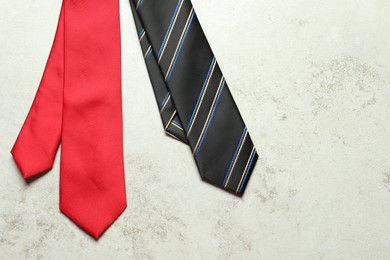 Photo of Two neckties on light textured table, top view. Space for text