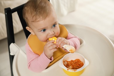 Cute little baby wearing bib while eating at home