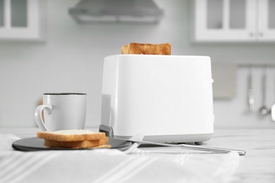 Photo of Modern toaster and tasty breakfast on white table in kitchen