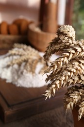 Photo of Wheat spikes against blurred background indoors, closeup. Space for text