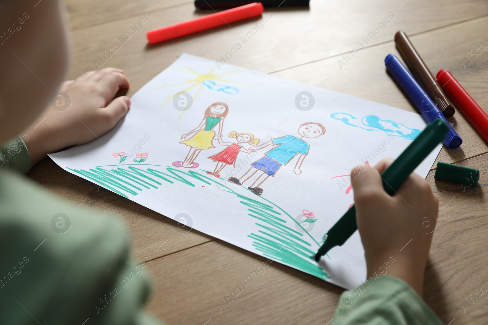 Photo of Little boy drawing picture with marker at wooden table, closeup. Child`s art