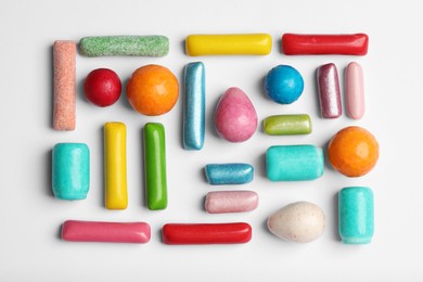 Many tasty bubble gums on white background, flat lay