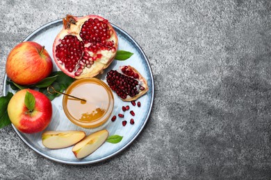Photo of Honey, pomegranate and apples on grey table, top view with space for text. Rosh Hashana holiday