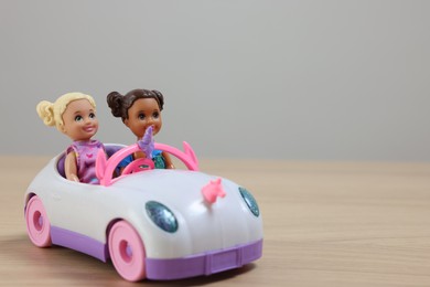 Leiden, Netherlands - September 20, 2023: Beautiful Chelsea dolls in toy car on wooden table against light gray background, space for text