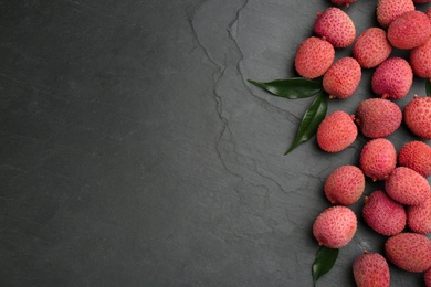 Fresh ripe lychee fruits on black table, flat lay. Space for text