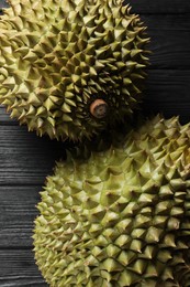 Photo of Ripe durians on black wooden table, closeup