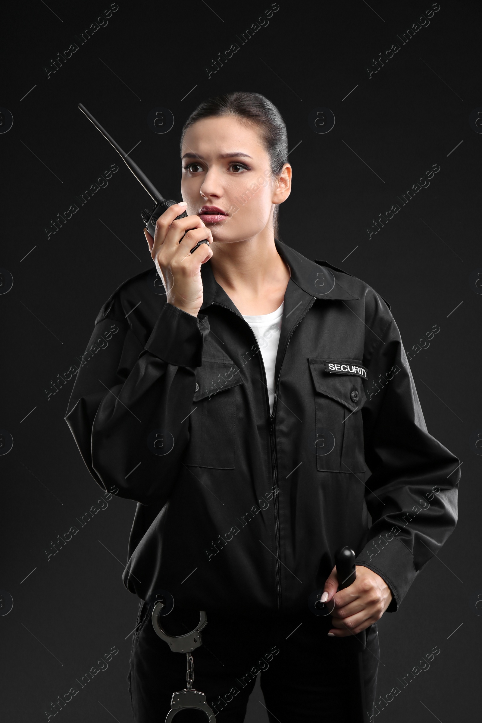 Photo of Female security guard using portable radio transmitter on dark background