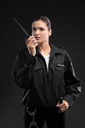 Photo of Female security guard using portable radio transmitter on dark background