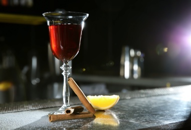 Photo of Fresh red cinnamon whiskey alcoholic cocktail on bar counter. Space for text