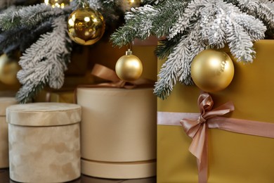 Photo of Many gift boxes under decorated Christmas tree at home, closeup