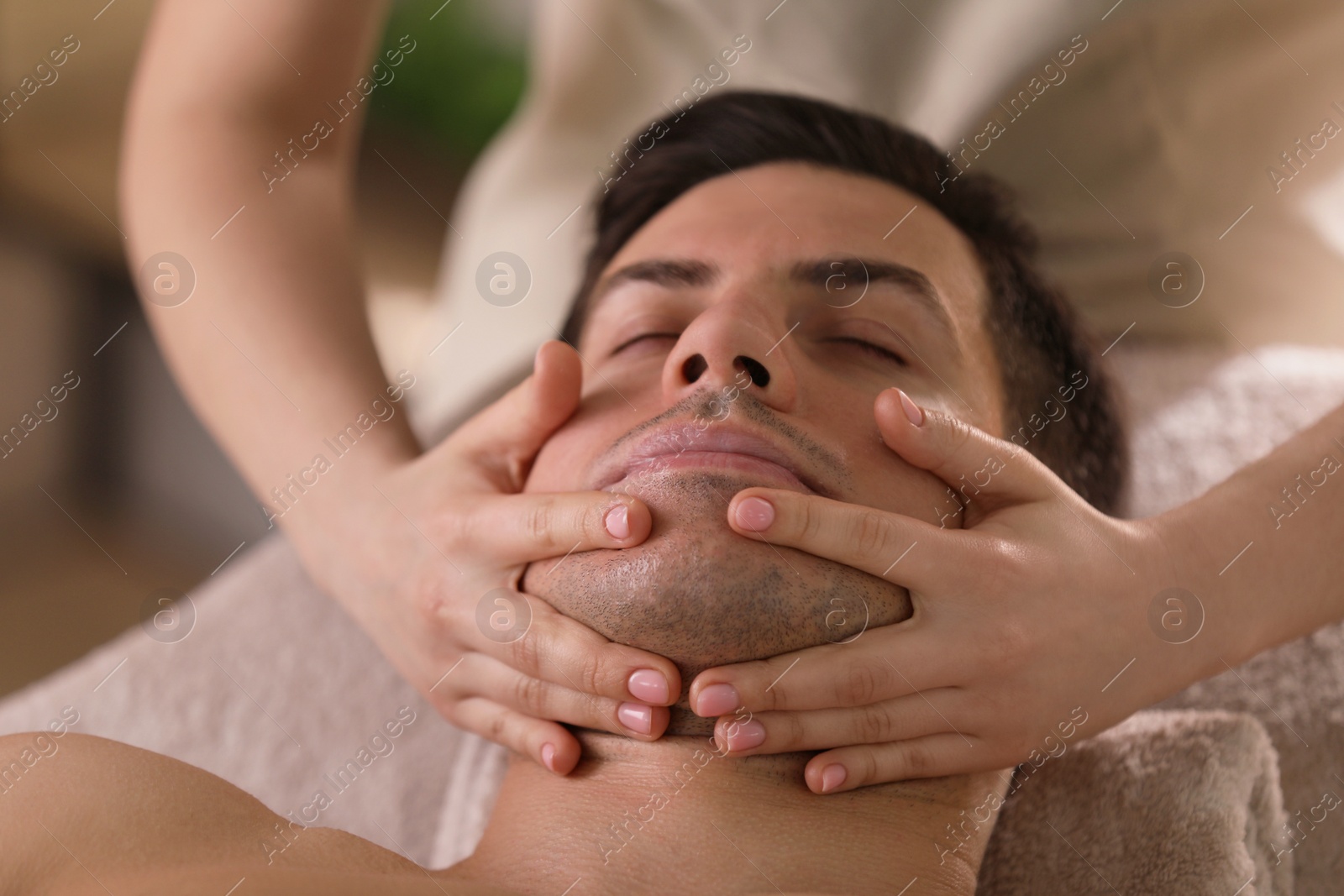 Photo of Man receiving facial massage in beauty salon, closeup