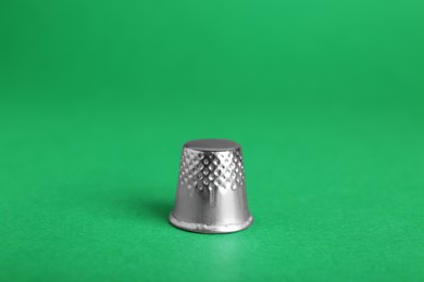 Silver thimble on green background. Sewing accessory