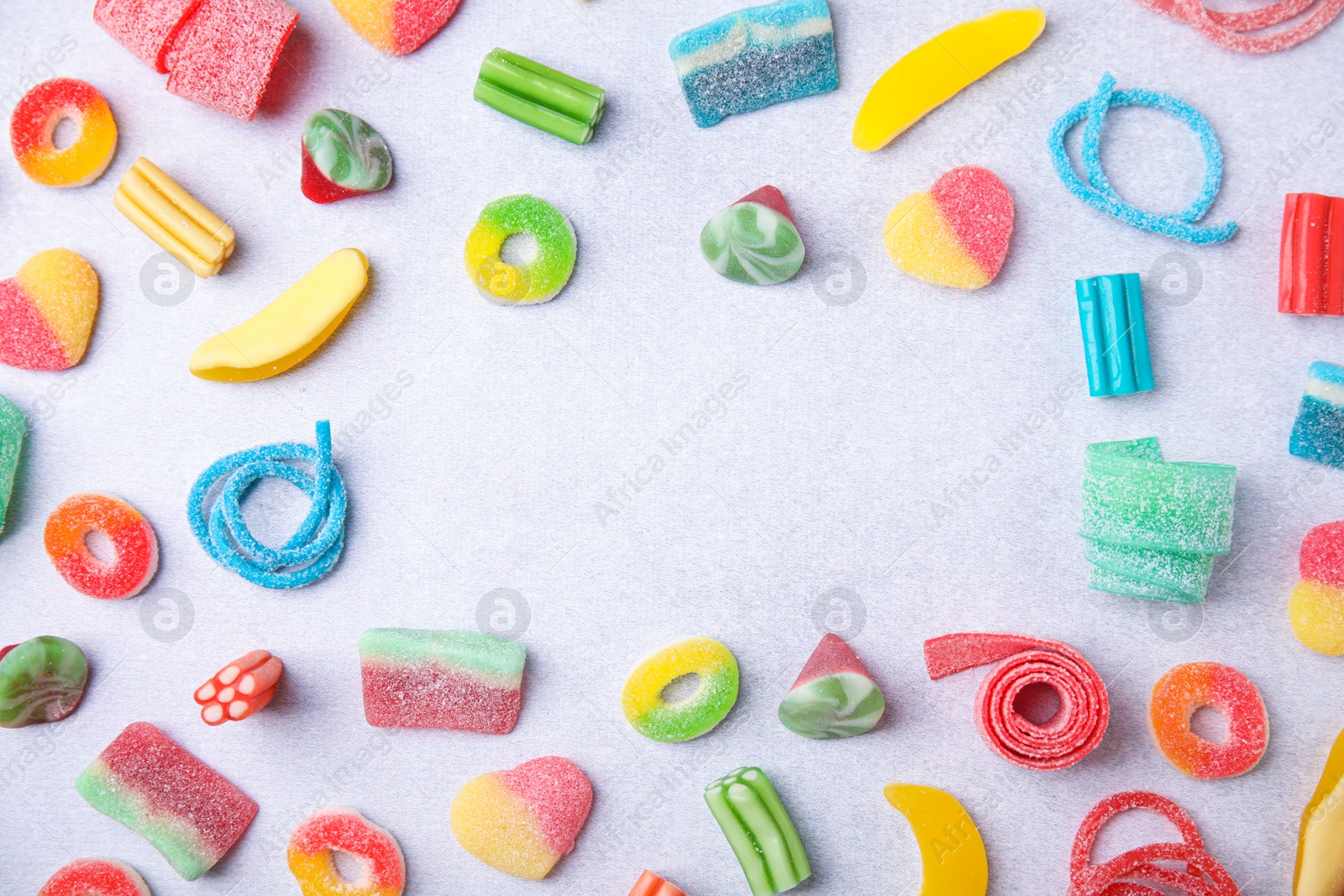 Photo of Frame of many tasty colorful jelly candies on white table, flat lay. Space for text