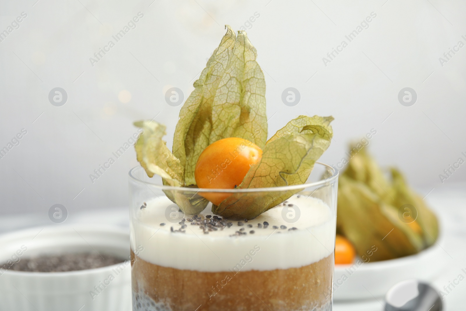 Photo of Delicious chia pudding decorated with physalis fruit on table, closeup