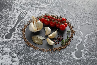 Different spices and silhouettes of cutlery and plate on grey marble background