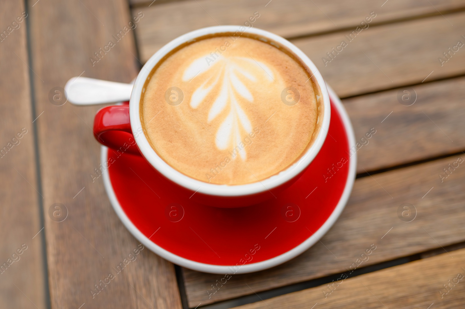 Photo of Cup of aromatic coffee on wooden table, above view