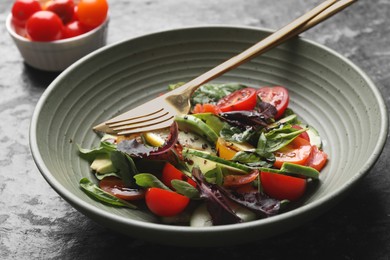 Delicious vegetable salad on black textured table, closeup