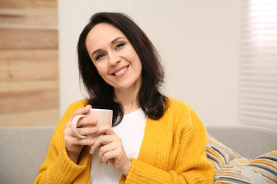 Photo of Beautiful mature woman with cup of coffee at home
