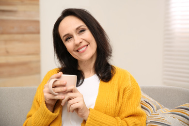 Beautiful mature woman with cup of coffee at home