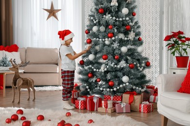 Photo of Cute little girl decorating Christmas tree at home