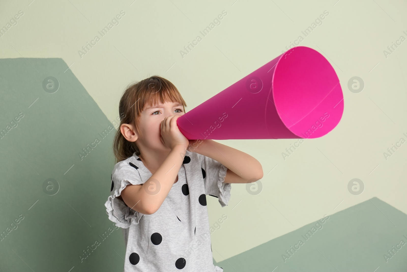 Photo of Cute little girl with paper megaphone on color background