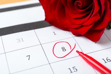 Photo of Rose and red marker on calendar near date 8th of March, closeup. International Women's Day