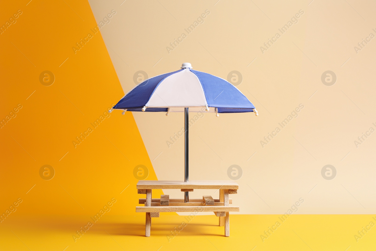 Photo of Small wooden holder with toy umbrella on color background