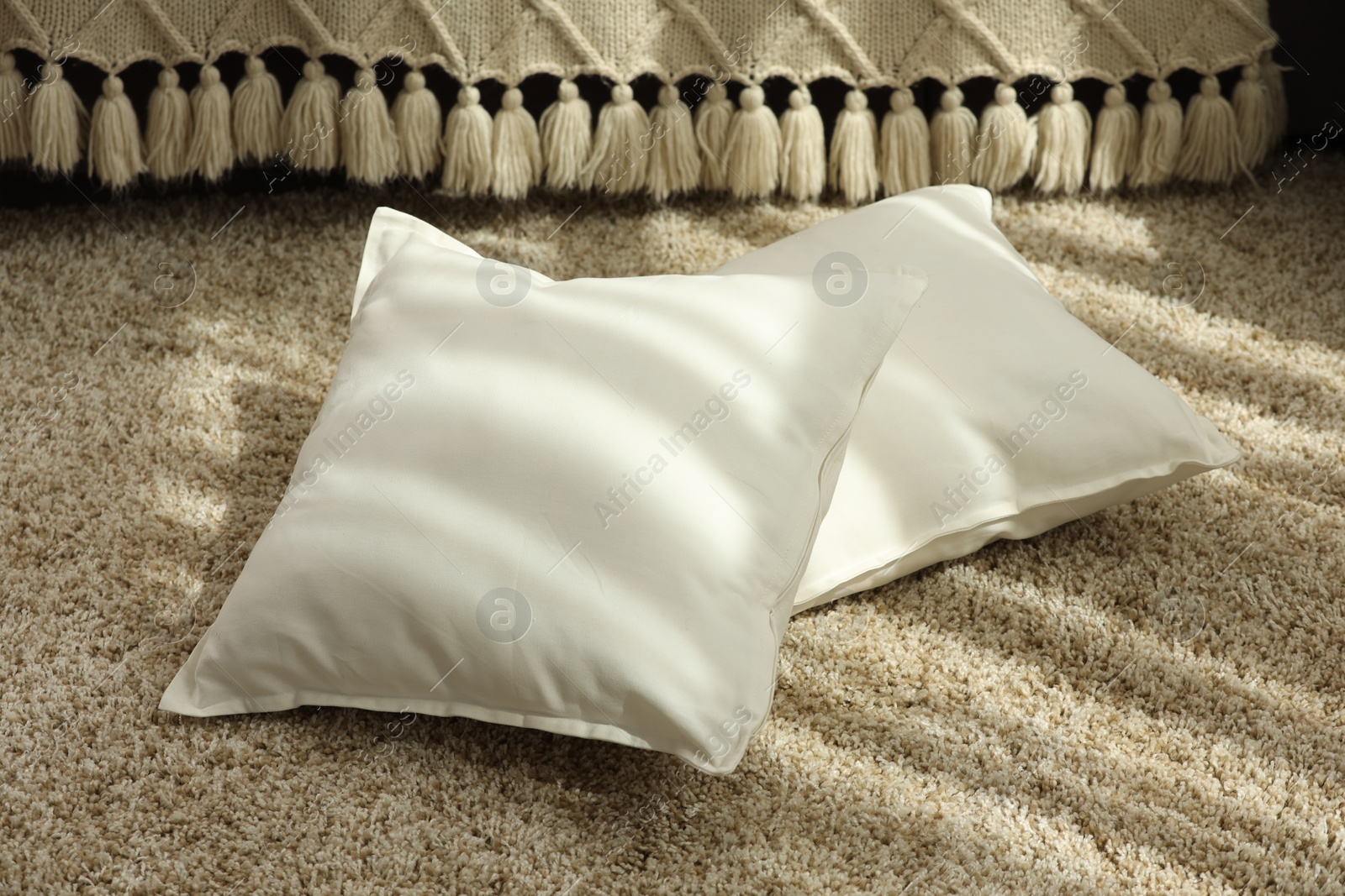 Photo of Soft white pillows on floor in room