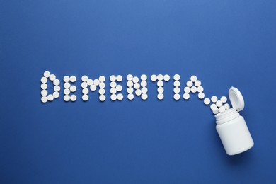 Photo of Word Dementia made of pills and bottle on blue background, flat lay