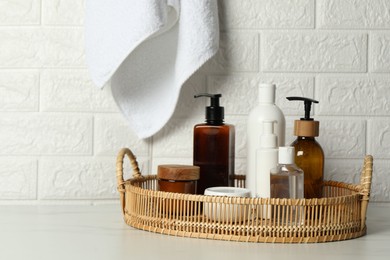 Photo of Different bath accessories and personal care products on white table near brick wall